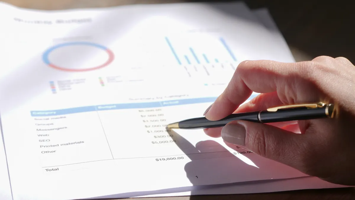 Hand pointing at data table on a report with charts
