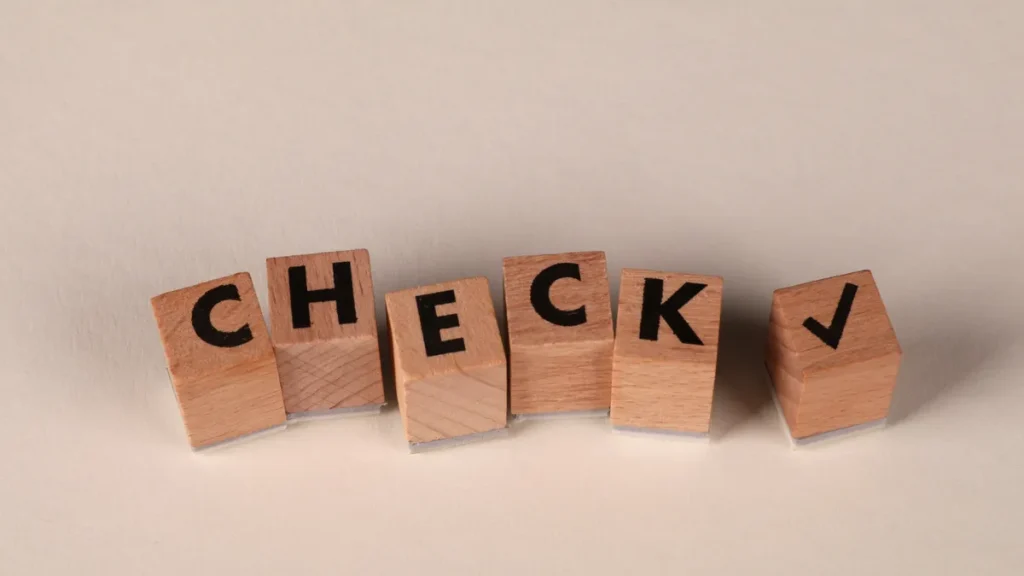 Wooden blocks spelling CHECK with a check mark