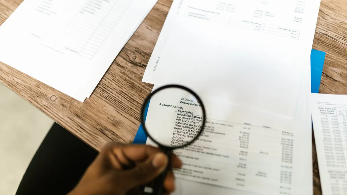 Person examining paperwork with a magnifying glass