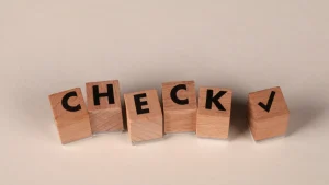 Wooden blocks spelling CHECK with a check mark
