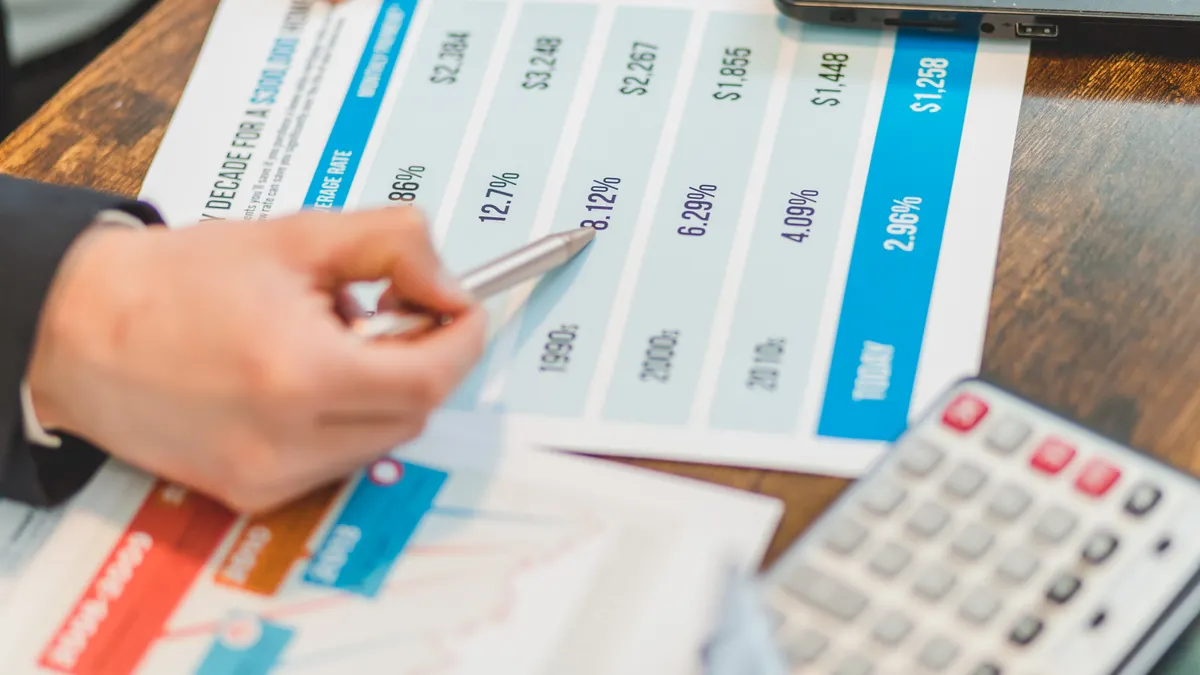 hand pointing at pricing chart with calculator