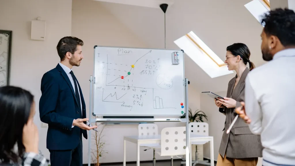 team reviewing a metrics chart on a whiteboard in an office